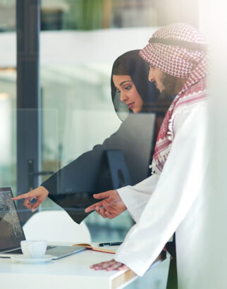 Business people, Arabic and pointing at laptop screen in office for consult, advice or client. Lens flare, hijab woman and man with keffiyeh for asset management, planning or idea at Investment bank.